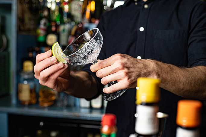 Bartender putting lime around the rim of a glass