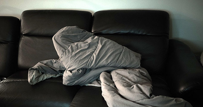 Couch with blanket crumpled on it